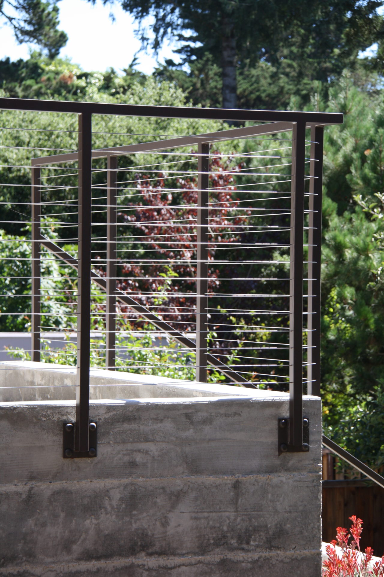 custom black metal cable railing installed to the exterior of a residential property. Beautiful view of trees from railing.