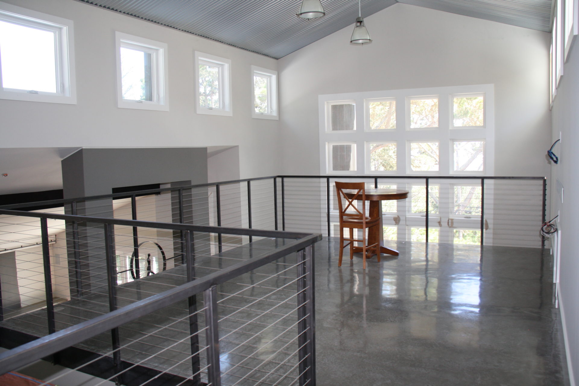 custom black metal railing installed to the top floor of a residential home in san mateo. House is white walled with black floor and coffee table in the center.