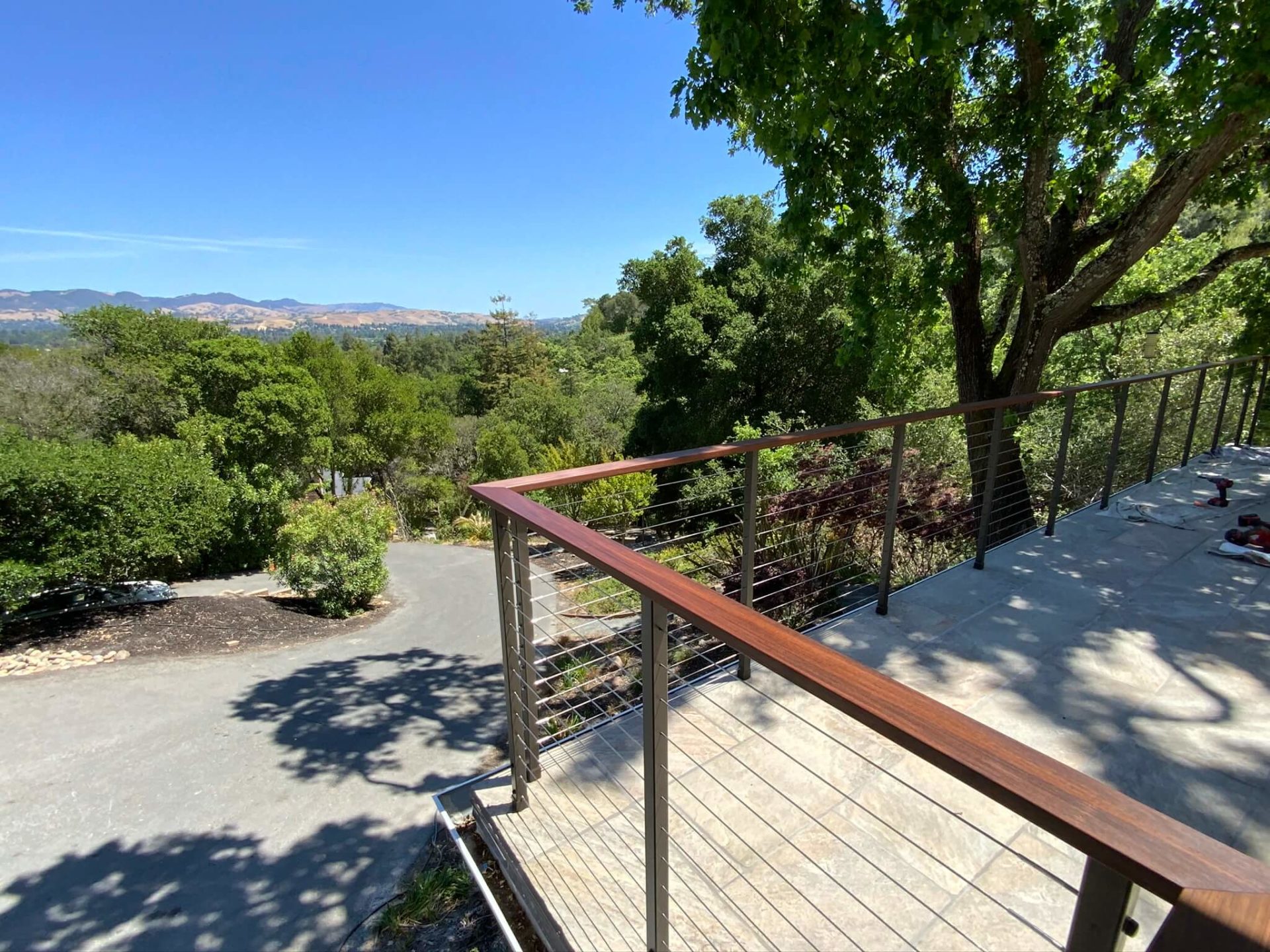 Cable railing system installed in San Rafael, CA with wooden top board and hilltop view