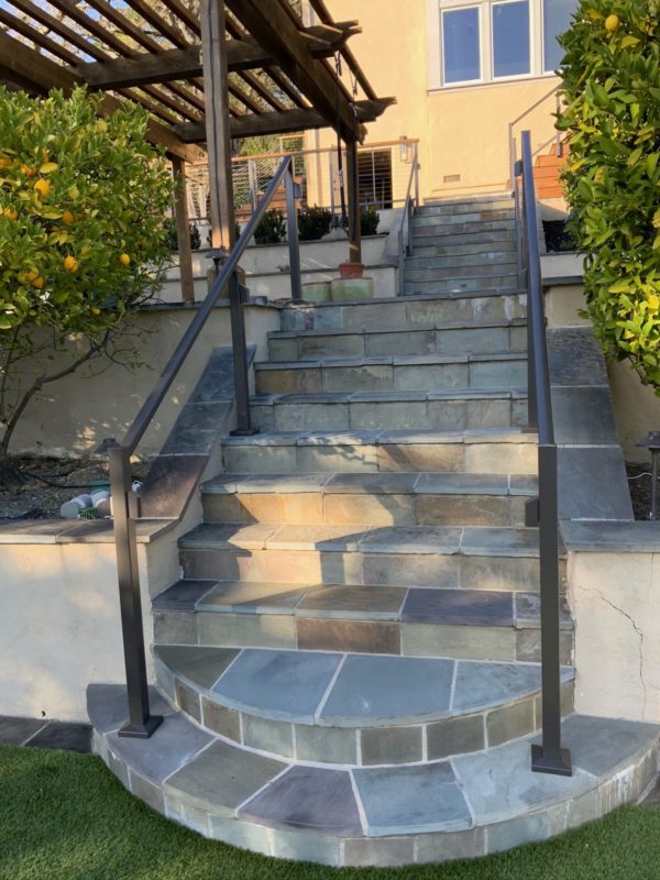 stone tile stairs with aluminum railing installation in residential backyard